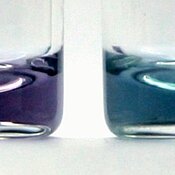 Two small vials with violett (left) and blue (right) solutions.