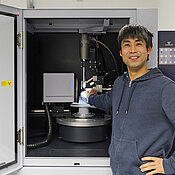 Crystallographer Dr Kazutaka Shoyama in front of his working tool, a single crystal diffractometer. (Image: Arbeitsgruppe Würthner / Universität Würzburg)