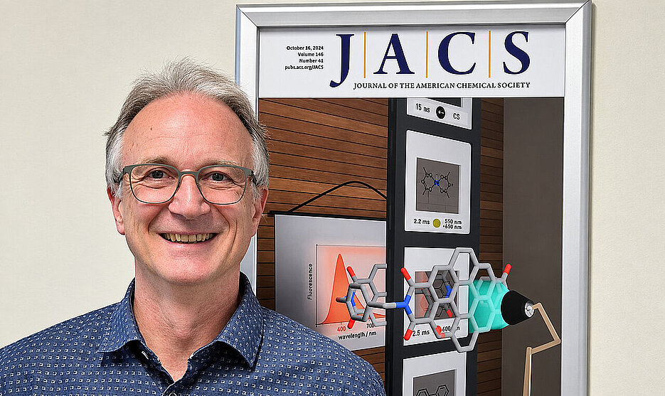 Portrait photo of Frank Würthner in front of a poster