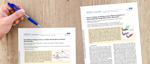 Two scientific articles of the Hertel group on a desk.