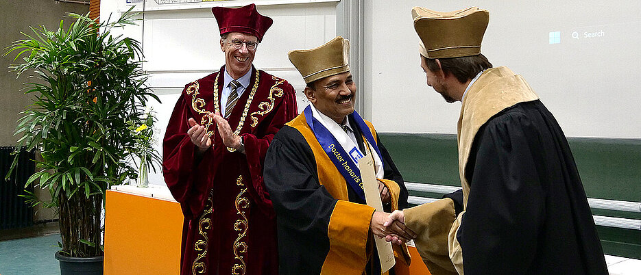 Dekan Holger Helten und Präsident Paul Pauli gratulieren Professor Jarugu Narasimha Moorthy zum Erhalt der Ehrendoktorwürde.