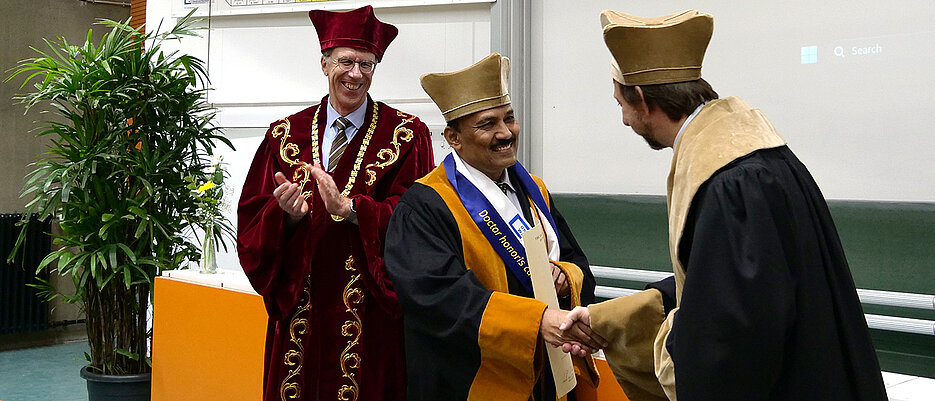 Dekan Holger Helten (re.) und Präsident Paul Pauli (li.) gratulieren Professor Jarugu Narasimha Moorthy zum Erhalt der Ehrendoktorwürde.